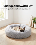 Dog curled up asleep in the light grey calming plush donut bed