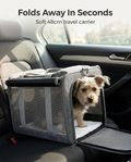 Small dog in the grey foldable soft travel carrier in a car
