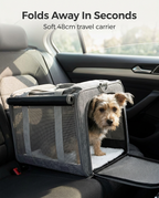 Small dog in the grey foldable soft travel carrier in a car