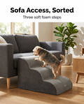 Small dog climbing the three step grey foam pet stairs to a sofa